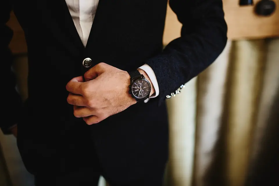 Un hombre con traje oscuro ajustándose el reloj