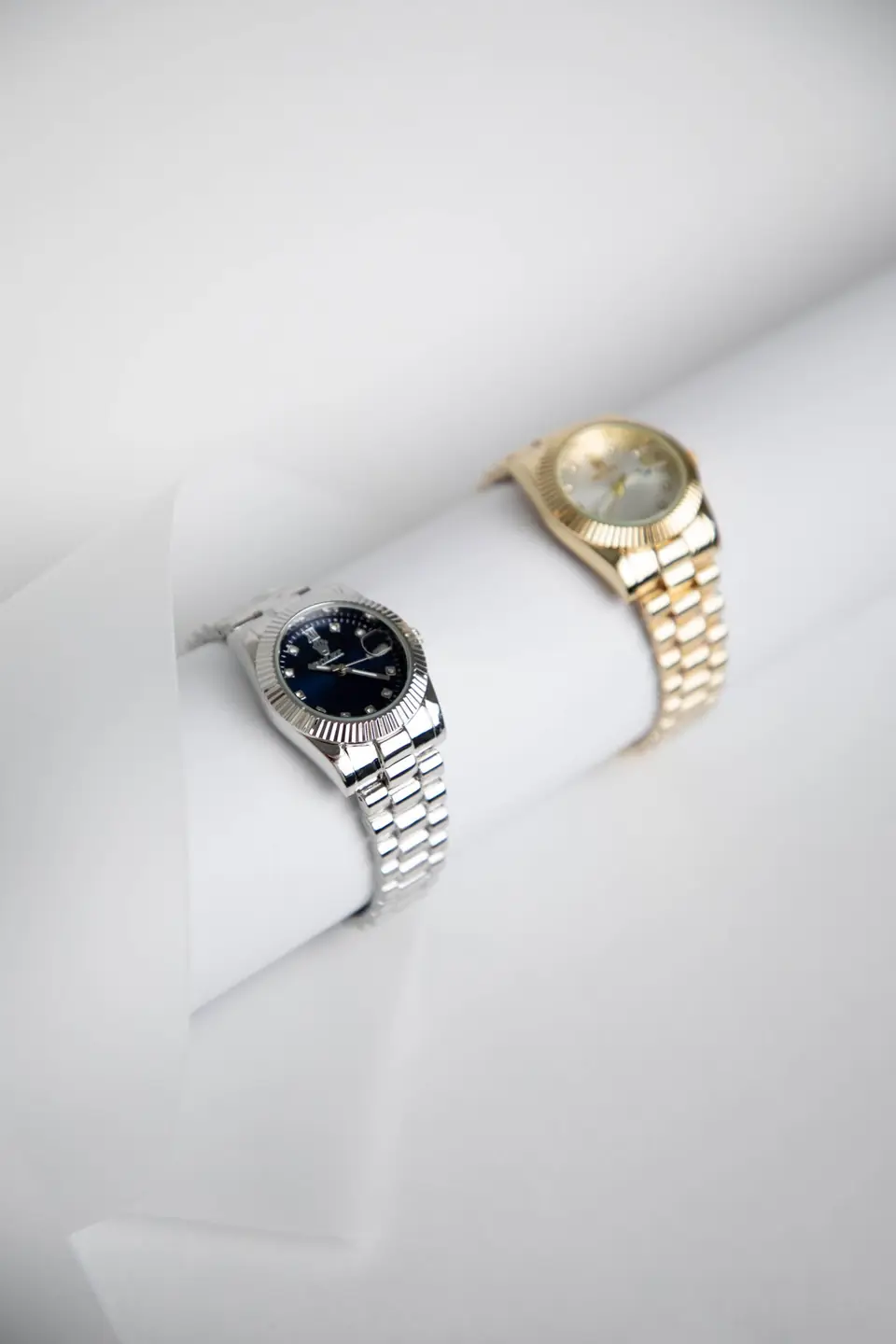 Dos relojes, uno de acero y otro de oro, sobre un fondo blanco