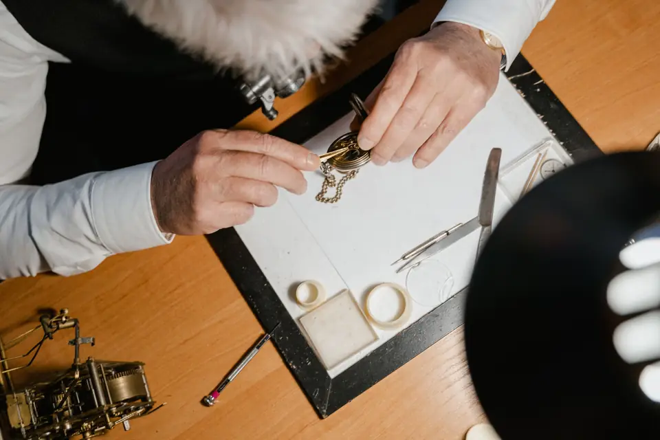 Manos revisando un reloj con una lupa de relojero